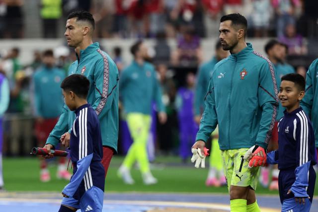 Portugal's forward #07 Cristiano Ronaldo (L) and goalkeeper #01 Diogo Costa (R) enter the field for the national anthems ahead the 2026 World Cup round of 16 football match between Portugal and Spain at the Dallas Stadium in Arlington on July 6, 2026. (Photo by Aric Becker / AFP)
