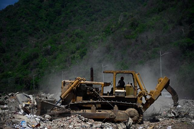 Heavy machinery clears debris from collapsed buildings in Caraballeda, La Guaira state, Venezuela, on July 6, 2026, following powerful earthquakes that struck the regio. The earthquakes that struck Venezuela on June 24 have claimed the lives of at least 3,342 people, the Venezuelan government reported on July 5. (Photo by Federico PARRA / AFP)