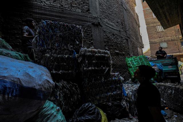 Egyptian workers load bails of plastic for recycling on a truck at the garbage city in the Manshiyet Nasser neighbourhood in Cairo on July 6, 2026. (Photo by Khaled DESOUKI / AFP)