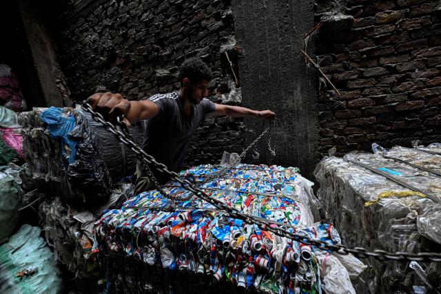 An Egyptian worker prepares to load a bail of plastic onto a truck for recycling at the garbage city in the Manshiyet Nasser neighbourhood in Cairo on July 6, 2026. (Photo by Khaled DESOUKI / AFP)