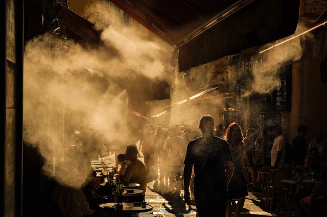 People walk down a street during a heatwave in the French Riviera city of Nice on July 6, 2026 (Photo by Valery HACHE / AFP)