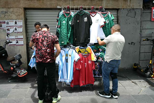 People buy football jerseys at a street stall during the 2026 FIFA World Cup round-of-16 football match between Portugal and Spain at the Zocalo square in Mexico City, Mexico, on July 6, 2026 (Photo by YURI CORTEZ / AFP)