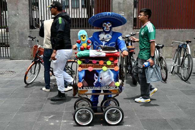 A Mexican traditional barrel organ player poses for a picture during the 2026 FIFA World Cup round-of-16 football match between Portugal and Spain, nearby the Zocalo square in Mexico City, Mexico, on July 6, 2026 (Photo by YURI CORTEZ / AFP)