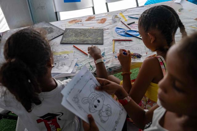 Children displaced by the June 24 earthquake colour drawings at a temporary shelter set up at the Jose Maria Vargas sports complex in Catia la Mar, La Guaira state, Venezuela, on July 6, 2026. The twin earthquakes that struck Venezuela on June 24 have claimed the lives of at least 3,535 people, the Venezuelan government reported on July 5. (Photo by Miguel MEDINA / AFP)