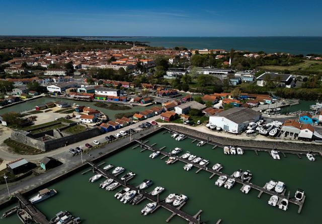 (FILES) This aerial view shows boats moored in the harbour of Le Chateau-d'Oleron with the city in background, on the Island of Oleron, south-western France, on April 8, 2025. France's Constitutional Council is set to review on July 7, 2026, a priority constitutional challenge (Question prioritaire de constitutionnalité) raised by Airbnb in its dispute with the municipality of the south-western island of Oleron. On April 2025, the short-term rental giant was ordered to pay more than 8.6 million euros to the local authority over violations relating to the collection of the tourist tax. (Photo by Philippe LOPEZ / AFP)