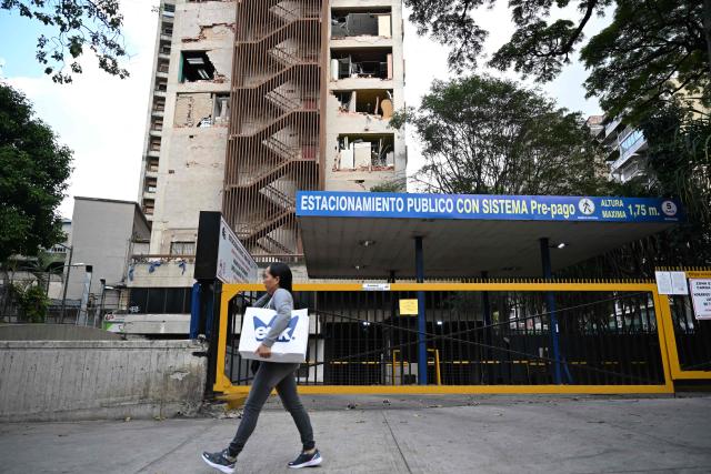 A woman walks past a damaged building in Chacao municipality, Caracas, on July 6, 2026, following the June 24 earthquakes that hit the region. The death toll from Venezuela's twin earthquakes has risen to 3,535, with more than 16,700 injured in the disaster, according to updated official figures released on July 6. (Photo by Raul ARBOLEDA / AFP)