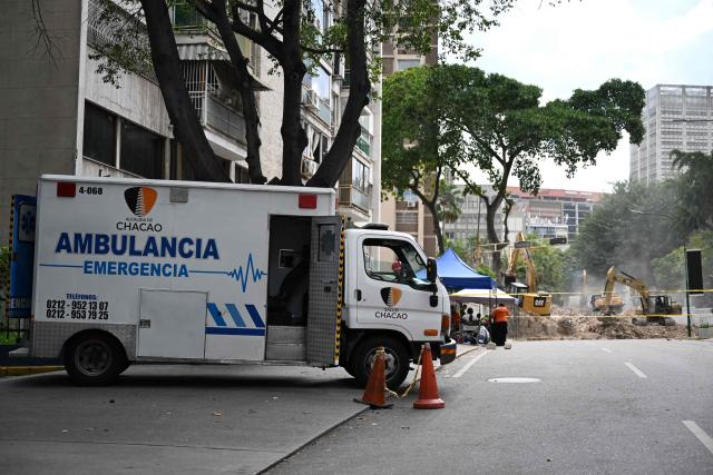 An ambulance s parke nearby heavy machinery removing debris form a collapsed building at the Chacao municipality in Caracas, on July 6, 2026, following the June 24 earthquakes that hit the region. The death toll from Venezuela's twin earthquakes has risen to 3,535, with more than 16,700 injured in the disaster, according to updated official figures released on July 6. (Photo by Raul ARBOLEDA / AFP)