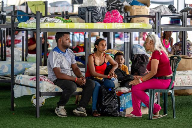 Displaced people sit and talk beside bunk beds inside a temporary shelter set up at the Jose Maria Vargas sports complex in Catia la Mar, La Guaira state, Venezuela, on July 6, 2026, following the June 24 earthquakes. The twin earthquakes that struck Venezuela on June 24 have claimed the lives of at least 3,535 people, the Venezuelan government reported on July 6. (Photo by Miguel MEDINA / AFP)