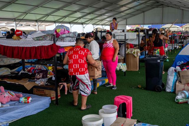 People displaced by the June 24 earthquakes stand and gather around bunk beds inside a temporary shelter set up at the Jose Maria Vargas sports complex in Catia la Mar, La Guaira state, Venezuela, on July 6, 2026. The twin earthquakes that struck Venezuela on June 24 have claimed the lives of at least 3,535 people, the Venezuelan government reported on July 6. (Photo by Miguel MEDINA / AFP)