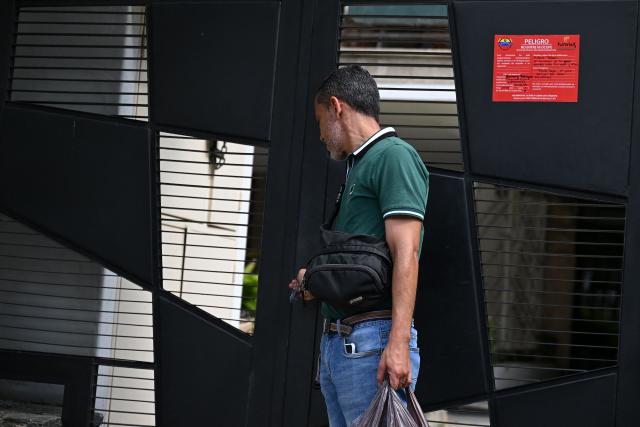 A resident leaves after an official inspection declared the building uninhabitable (red sign) in Caracas, on July 6, 2026, following the June 24 earthquakes that hit the region. The death toll from Venezuela's twin earthquakes has risen to 3,535, with more than 16,700 injured in the disaster, according to updated official figures released on July 6. (Photo by Raul ARBOLEDA / AFP)