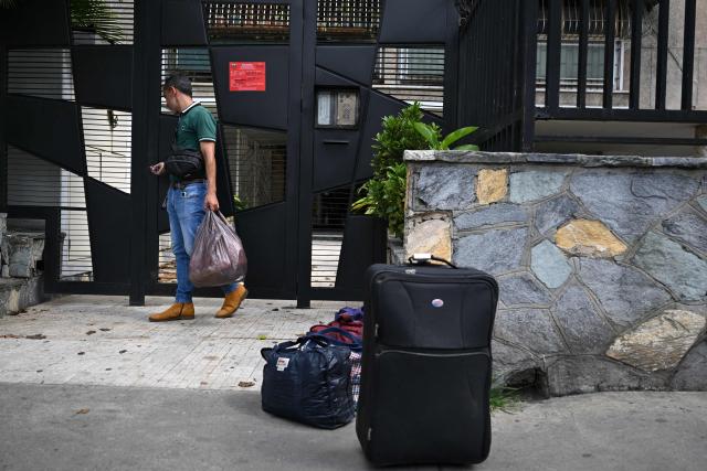 A resident leaves after an official inspection declared the building uninhabitable (red sign) in Caracas, on July 6, 2026, following the June 24 earthquakes that hit the region. The death toll from Venezuela's twin earthquakes has risen to 3,535, with more than 16,700 injured in the disaster, according to updated official figures released on July 6. (Photo by Raul ARBOLEDA / AFP)