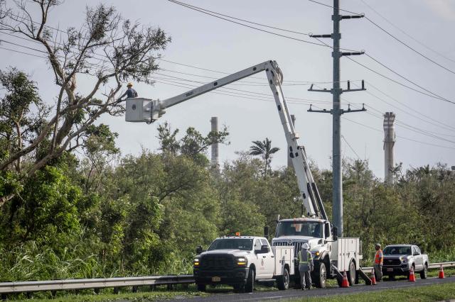 Workers remove a tree tangled in power lines after strong winds brought by Typhoon Bavi in Guam on July 7, 2026. (Photo by Yuichi YAMAZAKI / AFP)