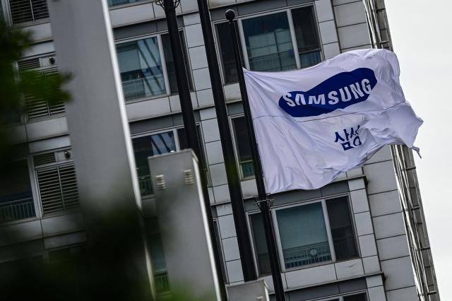 A Samsung flag flutters outside the Samsung Electronics Seocho building in Seoul on July 7, 2026. South Korean technology giant Samsung Electronics forecast on July 7 a roughly 19-fold jump in second-quarter operating profit from a year earlier, buoyed by sustained AI-driven demand for memory chips. (Photo by Jade GAO / AFP)