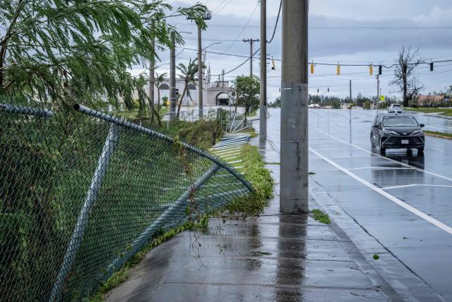 A fence along a sidewalk lies toppled after strong winds brought by Typhoon Bavi in Guam on July 7, 2026. (Photo by Yuichi YAMAZAKI / AFP)
