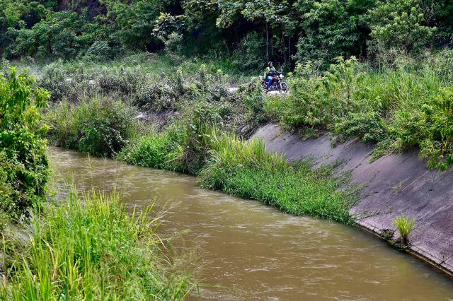 A motorcycle drives along the road adjacent to what is popularly known as the Canal de la Muerte(Death Canal), in northwest Guayaquil, Ecuador, on June 29, 2026. Hundreds of bodies linked to kidnapping victims, criminal acts, and clashes between gangs have been found at he Canal de la Muerte -a section of the Daule–Santa Elena transfer canal. (Photo by MARCOS PIN / AFP)