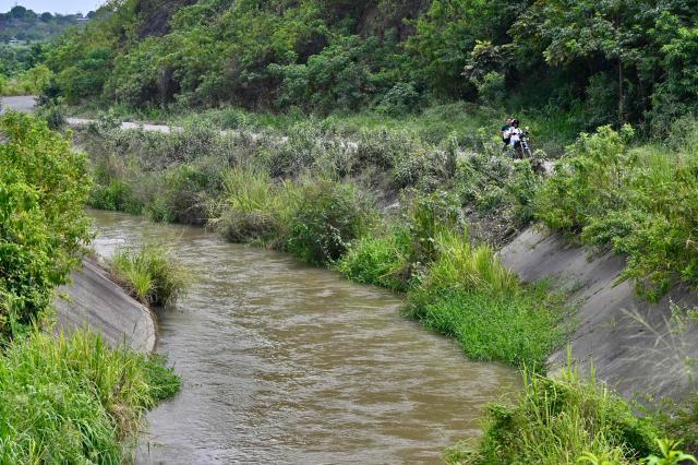 A motorcycle drives along the road adjacent to what is popularly known as the Canal de la Muerte(Death Canal), in northwest Guayaquil, Ecuador, on June 29, 2026. Hundreds of bodies linked to kidnapping victims, criminal acts, and clashes between gangs have been found at he Canal de la Muerte -a section of the Daule–Santa Elena transfer canal. (Photo by MARCOS PIN / AFP)