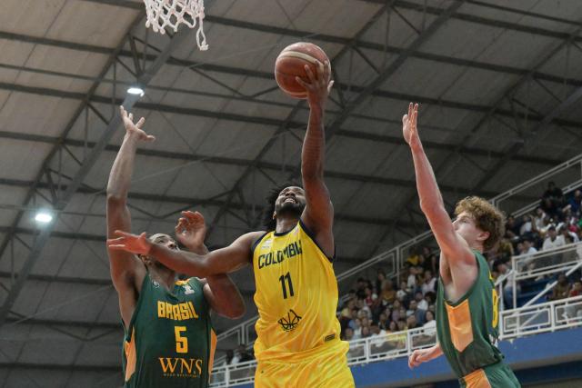 Colombia's Braian Angola (C) heads to the basket past Brazil's Bruno Caboclo (L) and Leo Beath during the FIBA Basketball World Cup 2027 Americas qualifiers Group C match between Colombia and Brazil, at the Evangelista Mora Colisseum in Cali, Valle del Cauca, Colombia, on July 6, 2026. (Photo by JOAQUIN SARMIENTO / AFP)