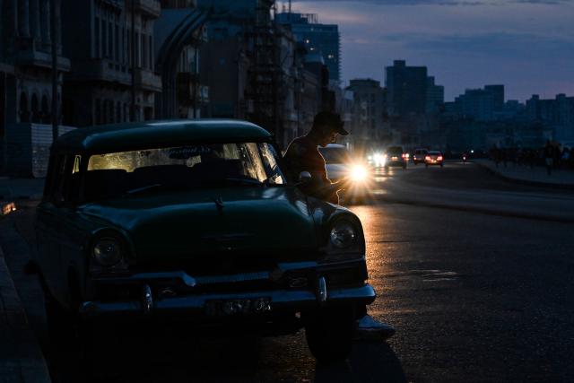 A man looks at a mobile phone in Havana during a nationwide blackout on July 6, 2026. Cuba on July 6 suffered its third nationwide power outage since the start of the year, the state electricity company said. The impoverished island was already struggling to keep the lights on before US President Donald Trump in January imposed an oil blockade, which has depleted the already dwindling supply of fuel for Cuba's power plants. (Photo by YAMIL LAGE / AFP)