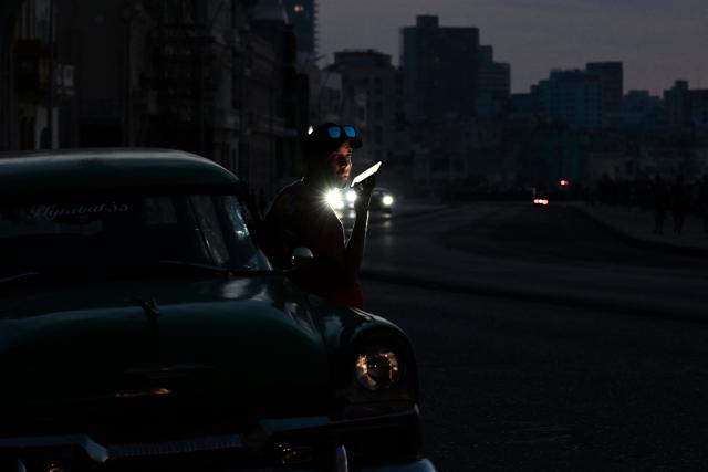 A man uses a mobile phone during a nationwide blackout in Havana on July 6, 2026. Cuba on July 6 suffered its third nationwide power outage since the start of the year, the state electricity company said. The impoverished island was already struggling to keep the lights on before US President Donald Trump in January imposed an oil blockade, which has depleted the already dwindling supply of fuel for Cuba's power plants. (Photo by YAMIL LAGE / AFP)