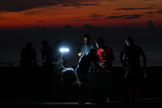 People gather along the Malecon during a nationwide blackout in Havana on July 6, 2026. Cuba on July 6 suffered its third nationwide power outage since the start of the year, the state electricity company said. The impoverished island was already struggling to keep the lights on before US President Donald Trump in January imposed an oil blockade, which has depleted the already dwindling supply of fuel for Cuba's power plants. (Photo by YAMIL LAGE / AFP)