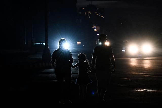 People walk along a street during a nationwide blackout in Havana on July 6, 2026. Cuba on July 6 suffered its third nationwide power outage since the start of the year, the state electricity company said. The impoverished island was already struggling to keep the lights on before US President Donald Trump in January imposed an oil blockade, which has depleted the already dwindling supply of fuel for Cuba's power plants. (Photo by YAMIL LAGE / AFP)