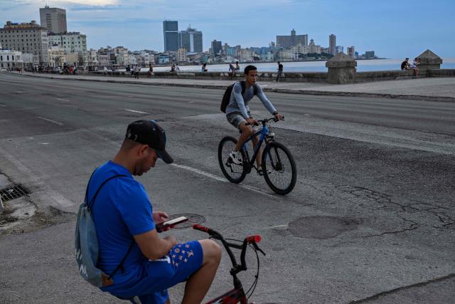 People ride and sit on bicycles along the Malecon during a nationwide blackout in Havana on July 6, 2026. Cuba on July 6 suffered its third nationwide power outage since the start of the year, the state electricity company said. The impoverished island was already struggling to keep the lights on before US President Donald Trump in January imposed an oil blockade, which has depleted the already dwindling supply of fuel for Cuba's power plants. (Photo by YAMIL LAGE / AFP)