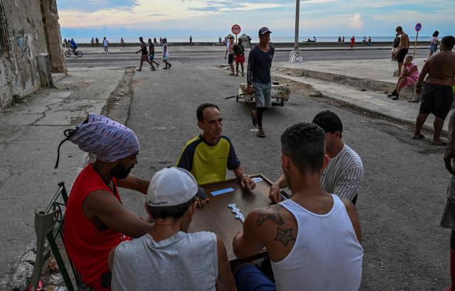 People play dominoes along a street near the Malecon during a nationwide blackout in Havana on July 6, 2026. Cuba on July 6 suffered its third nationwide power outage since the start of the year, the state electricity company said. The impoverished island was already struggling to keep the lights on before US President Donald Trump in January imposed an oil blockade, which has depleted the already dwindling supply of fuel for Cuba's power plants. (Photo by YAMIL LAGE / AFP)