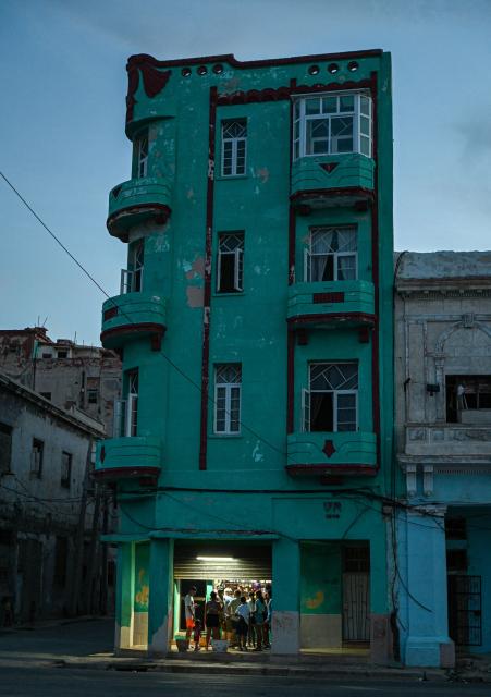A private business is lit by an electric generator while the rest of the building remains dark during a nationwide blackout in Havana on July 6, 2026. Cuba on July 6 suffered its third nationwide power outage since the start of the year, the state electricity company said. The impoverished island was already struggling to keep the lights on before US President Donald Trump in January imposed an oil blockade, which has depleted the already dwindling supply of fuel for Cuba's power plants. (Photo by ADALBERTO ROQUE / AFP)