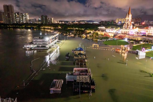 A flooded riverside walkway and shops are seen near a wharf on the Yongjiang river in Nanning, in China’s southern Guangxi region on July 6, 2026. Heavy rains and severe flooding from Typhoon Maysak killed at least two people in the southern region of Guangxi, and prompted authorities to evacuate at least 48,000 people as of July 6 evening. (Photo by CN-STR / AFP) / China OUT
