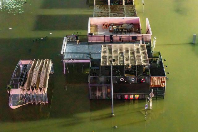 A woman stands on the rooftop of a flooded shop near a wharf on the Yongjiang river in Nanning, in China’s southern Guangxi region on July 6, 2026. Heavy rains and severe flooding from Typhoon Maysak killed at least two people in the southern region of Guangxi, and prompted authorities to evacuate at least 48,000 people as of July 6 evening. (Photo by CN-STR / AFP) / China OUT