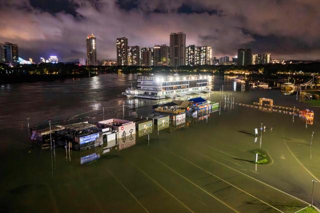A flooded riverside walkway and shops are seen near a wharf on the Yongjiang river in Nanning, in China’s southern Guangxi region on July 6, 2026. Heavy rains and severe flooding from Typhoon Maysak killed at least two people in the southern region of Guangxi, and prompted authorities to evacuate at least 48,000 people as of July 6 evening. (Photo by CN-STR / AFP) / China OUT