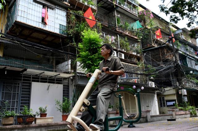 A man exercises in front of an old apartment complex in Hanoi on July 7, 2026. (Photo by Nhac NGUYEN / AFP)