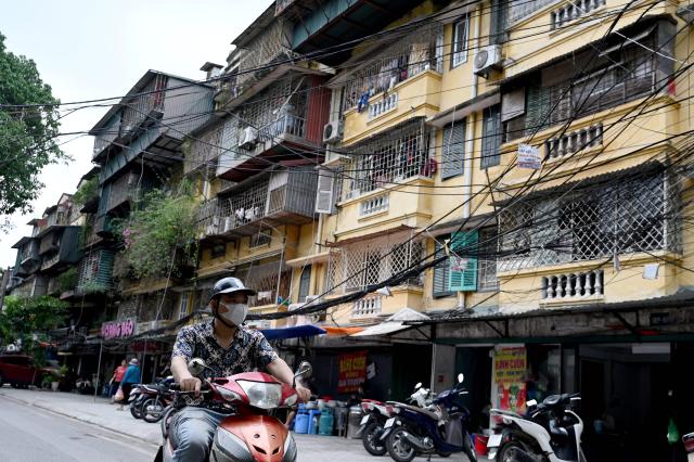 A man rides a motorbike past an old apartment complex in Hanoi on July 7, 2026. (Photo by Nhac NGUYEN / AFP)