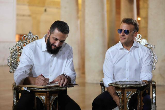 Syrian President Ahmed Al-Charaa (L) signs a book next to France's President Emmanuel Macron during a visit to the Umayyad Mosque in Damascus, on July 6, 2026. French President Emmanuel Macron arrived in Damascus on July 6, 2026 for the first visit by a Western European head of state since Syria's new authorities took power in 2024, an AFP journalist said. Macron, who will depart on July 7, 2026, will advocate for "a free, pluralist Syria that respects each of its components" and plays a role in moderating Middle East tensions, the French presidency told journalists ahead of his arrival. (Photo by Ludovic MARIN / AFP)