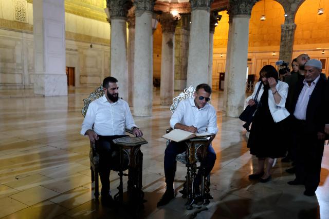 France's President Emmanuel Macron (R) signs a book next to Syrian President Ahmed Al-Charaa during a visit to the Umayyad Mosque in Damascus, on July 6, 2026. French President Emmanuel Macron arrived in Damascus on July 6, 2026 for the first visit by a Western European head of state since Syria's new authorities took power in 2024, an AFP journalist said. Macron, who will depart on July 7, 2026, will advocate for "a free, pluralist Syria that respects each of its components" and plays a role in moderating Middle East tensions, the French presidency told journalists ahead of his arrival. (Photo by Ludovic MARIN / AFP)