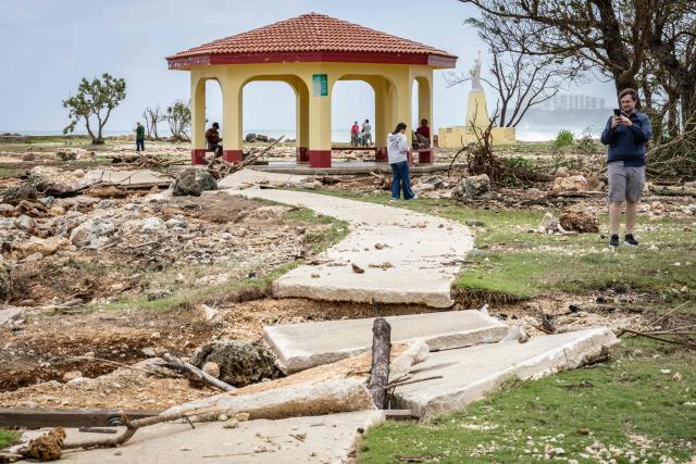 A man takes photographs of a damaged walkway at a park in the aftermath of Super Typhoon Bavi in Guam on July 7, 2026. (Photo by Yuichi YAMAZAKI / AFP)