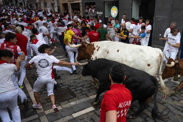 Participants run ahead of bulls from the Fuente Ymbro bull ranch during the first running of the bulls of the San Fermin festival in Pamplona, northern Spain, on July 7, 2026. Thousands of people every year attend the week-long festival and its famous 'encierros', or running of the bulls, in which six bulls are released at 8:00 a.m. evey day to run from their corral to the bullring through the narrow streets of the old town over an 850 meters (yards) course while runners ahead of them try to stay close to the bulls without falling over or being gored. (Photo by JORGE GUERRERO / AFP)