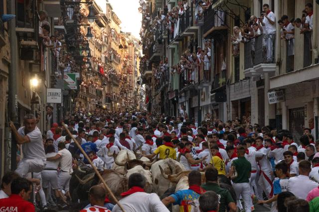 Participants run ahead of bulls from the Fuente Ymbro bull ranch during the first running of the bulls of the San Fermin festival in Pamplona, northern Spain, on July 7, 2026. Thousands of people every year attend the week-long festival and its famous 'encierros', or running of the bulls, in which six bulls are released at 8:00 a.m. evey day to run from their corral to the bullring through the narrow streets of the old town over an 850 meters (yards) course while runners ahead of them try to stay close to the bulls without falling over or being gored. (Photo by JORGE GUERRERO / AFP)