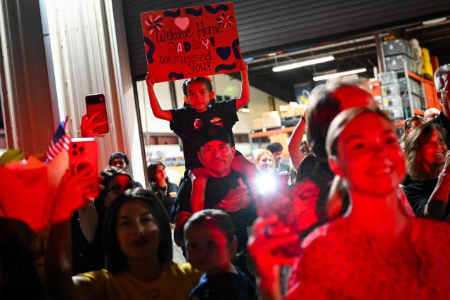 A child holds a sign for her dad as busses arrive with the Los Angeles County Fire Department USA-2 international urban search and rescue team to reunite them with their families after returning from rescue efforts following the earthquakes in Venezuela at the LACoFD Technical Operations Section in Los Angeles, California on July 6, 2026. (Photo by Patrick T. Fallon / AFP)