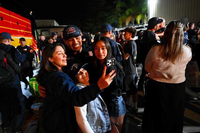 A member of the Los Angeles County Fire Department USA-2 international urban search and rescue team is reunited with his family after returning from rescue efforts following the earthquakes in Venezuela at the LACoFD Technical Operations Section in Los Angeles, California on July 6, 2026. (Photo by Patrick T. Fallon / AFP)