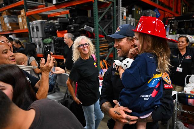 A member of the Los Angeles County Fire Department USA-2 international urban search and rescue team is reunited with his family after returning from rescue efforts following the earthquakes in Venezuela at the LACoFD Technical Operations Section in Los Angeles, California on July 6, 2026. (Photo by Patrick T. Fallon / AFP)