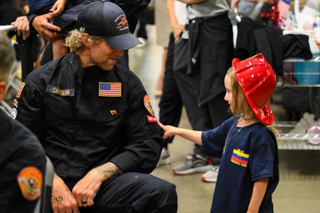 A member of the Los Angeles County Fire Department USA-2 international urban search and rescue team is reunited with his family after returning from rescue efforts following the earthquakes in Venezuela at the LACoFD Technical Operations Section in Los Angeles, California on July 6, 2026. (Photo by Patrick T. Fallon / AFP)