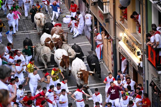Participants run ahead of bulls from the Fuente Ymbro bull ranch during the first running of the bulls of the San Fermin festival in Pamplona, northern Spain, on July 7, 2026. Thousands of people every year attend the week-long festival and its famous 'encierros', or running of the bulls, in which six bulls are released at 8:00 a.m. evey day to run from their corral to the bullring through the narrow streets of the old town over an 850 meters (yards) course while runners ahead of them try to stay close to the bulls without falling over or being gored. (Photo by Ander GILLENEA / AFP)