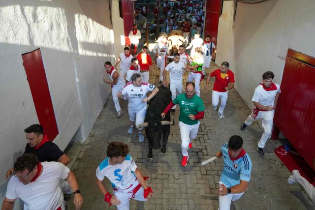Participants run next to a bull from the Fuente Ymbro bull ranch in a tunnel leading to the bullring during the first running of the bulls of the San Fermin festival in Pamplona, northern Spain, on July 7, 2026. Thousands of people every year attend the week-long festival and its famous 'encierros', or running of the bulls, in which six bulls are released at 8:00 a.m. evey day to run from their corral to the bullring through the narrow streets of the old town over an 850 meters (yards) course while runners ahead of them try to stay close to the bulls without falling over or being gored. (Photo by CESAR MANSO / AFP)