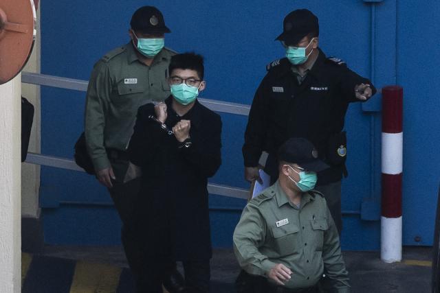 (FILES) Pro-democracy activist Joshua Wong (2nd L, in handcuffs) leaves the Lai Chi Kok reception centre in Hong Kong on December 18, 2020, on his way to court to face charges of knowingly taking part in an unauthorised assembly on October 5, 2019 during a protest against a mask ban. Prominent Hong Kong pro-democracy activist Joshua Wong -- already serving a years-long jail term for subversion -- will be sentenced in September 2026 in a separate national security case, according to a court website. (Photo by ISAAC LAWRENCE / AFP)