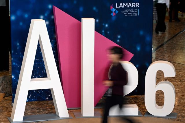 A woman walks past a logo of the Lamarr Conference at the World Conference Centre in Bonn, western Germany, on July 7, 2026. The Lamarr Conference is an international conference on artificial intelligence running from July 7-8 and bringing together "those shaping scientific foundations and those translating AI advances into tangible impact". In recognition of his achievements in AI research, development and knowledge transfer, the 2026 Lamarr Award will be presented to Jaroslaw Kutylowski, CEO and founder of German AI research company DeepL known for its language AI platform including DeepL Translator and for DeepL Agent. (Photo by Ina FASSBENDER / AFP)