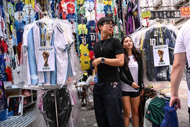 Customers look at unlicensed football jerseys on sale in a street market in Hong Kong on July 7 2026. (Photo by Peter PARKS / AFP)