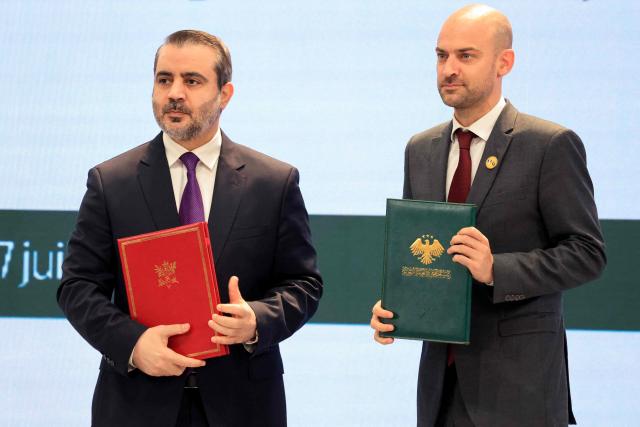 Syria's Foreign Affairs Minister Asaad al-Shaibani (L) and France's Foreign Affairs Minister Jean-Noel Barrot pose holding the Framework Agreement on Bilateral Cooperation during an agreement signing ceremony in Damascus on July 7, 2026. French President Emmanuel Macron arrived in Damascus on July 6, 2026 for the first visit by a Western European head of state since Syria's new authorities took power in 2024, an AFP journalist said. Macron, who will depart on July 7, 2026, will advocate for "a free, pluralist Syria that respects each of its components" and plays a role in moderating Middle East tensions, the French presidency told journalists ahead of his arrival. (Photo by Ludovic MARIN / POOL / AFP)