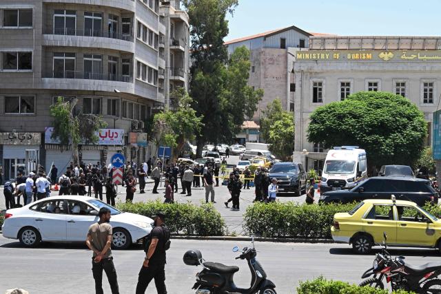 Security personnel stand guard near the Four Seasons Hotel following two blasts nearby in Damascus on July 7, 2026. Two explosions shook Damascus on July 7 near a hotel where French President Emmanuel Macron was staying, wounding at least 18 people, during the French leader's landmark visit to Syria. (Photo by LOUAI BESHARA / AFP)