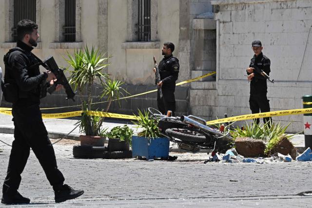 Security personnel stand guard near the Four Seasons Hotel following two blasts nearby in Damascus on July 7, 2026. Two explosions shook Damascus on July 7 near a hotel where French President Emmanuel Macron was staying, wounding at least 18 people, during the French leader's landmark visit to Syria. (Photo by LOUAI BESHARA / AFP)